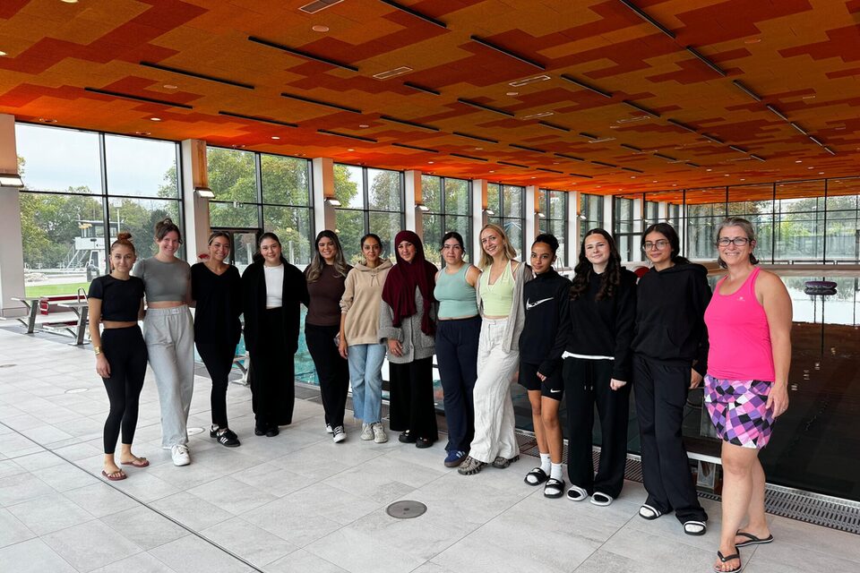 Die Betreuerinnen der Poolparty stehen im Schwimmbad vor dem Becken.