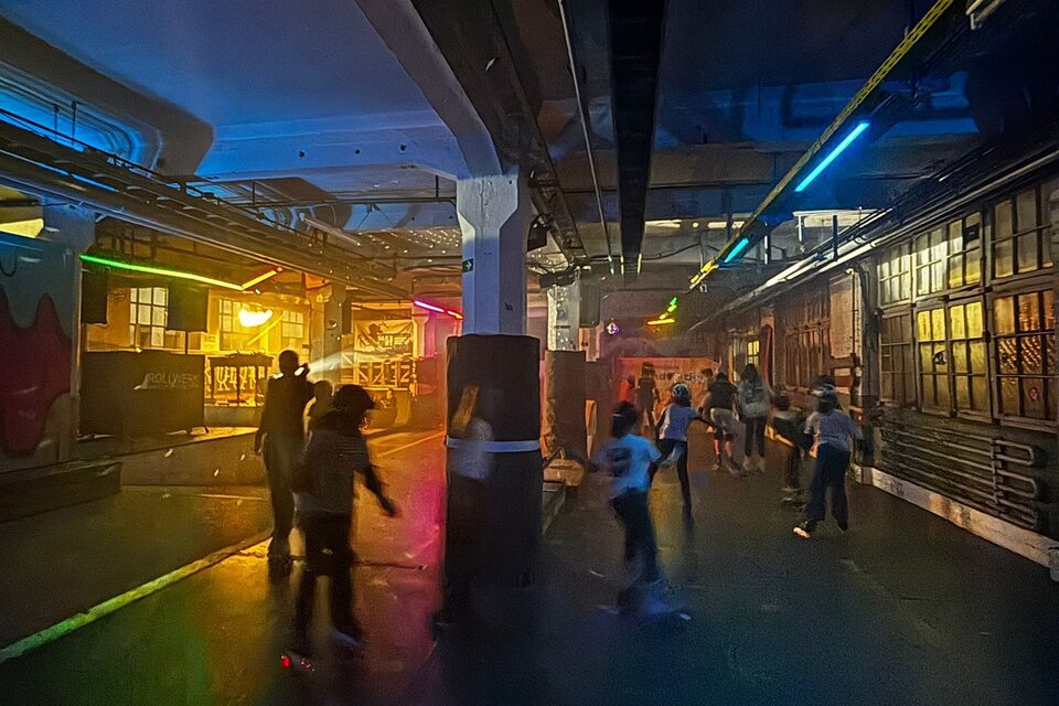 Jugendliche fahren Rollschuh in einer bunt beleuchteten Halle