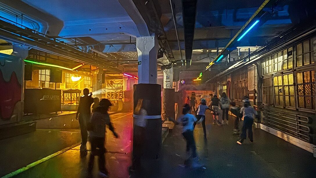 Jugendliche fahren Rollschuh in einer bunt beleuchteten Halle