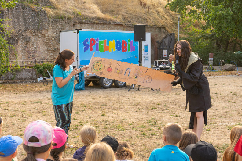 Zwei Mitarbeiterinnen der Jugendförderung eröffnen mit zahlreichen Kindern im Festungsgraben die Rüsselsheimer Ferienspiele