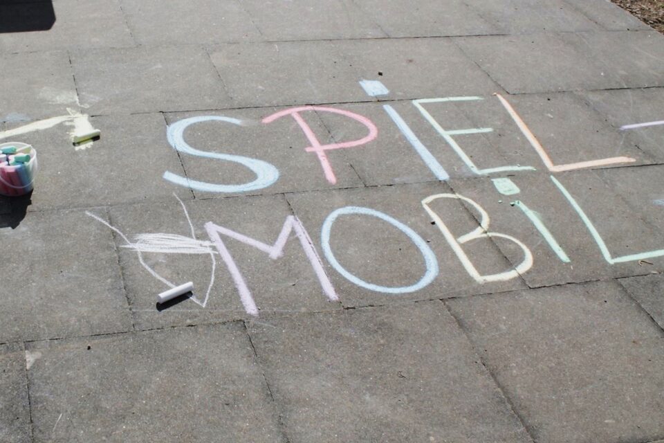 Auf dem Boden steht mit Kreide geschrieben Spielmobil