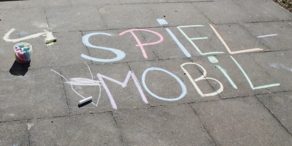 Auf dem Boden steht mit Kreide geschrieben Spielmobil
